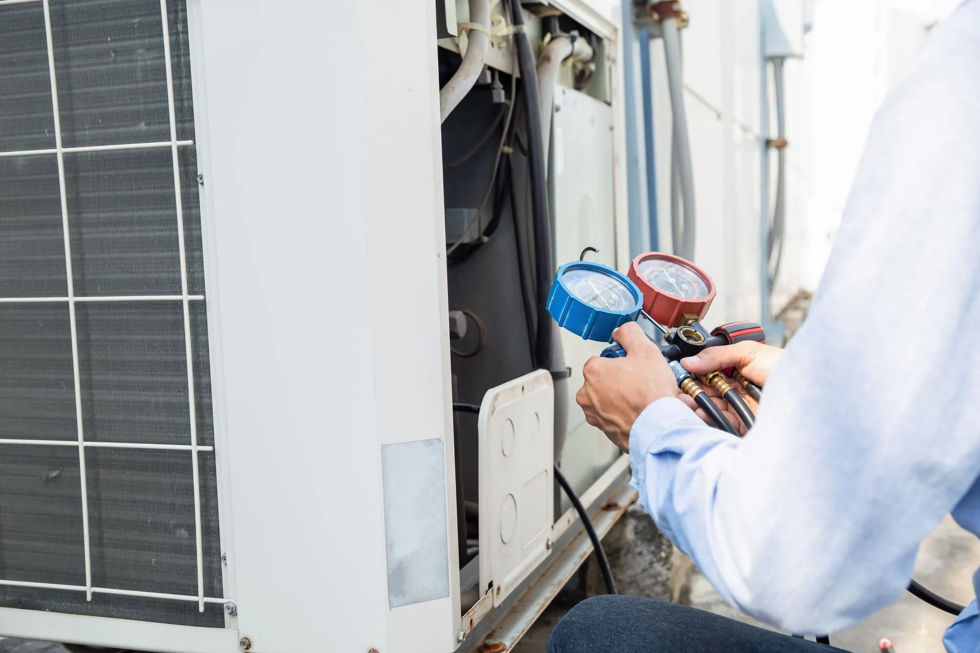 Technician performing a seasonal tune-up on a home air conditioning condenser.