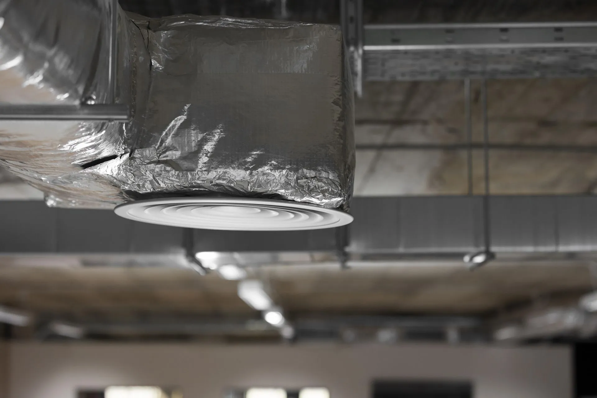 Technician sealing residential air conditioning ductwork to prevent air leaks.