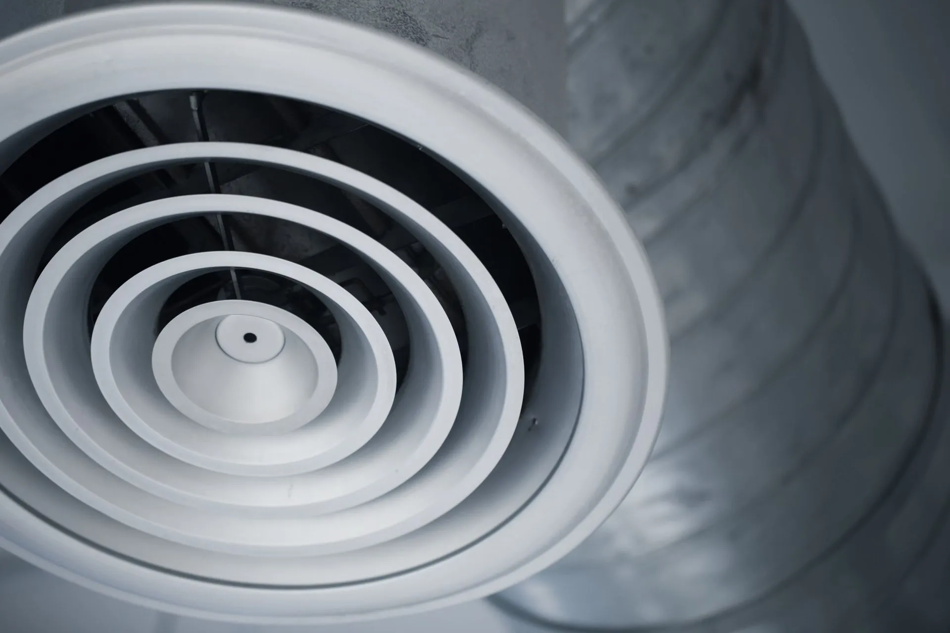 Close-up of a professional cleaning residential air ducts with a vacuum hose.