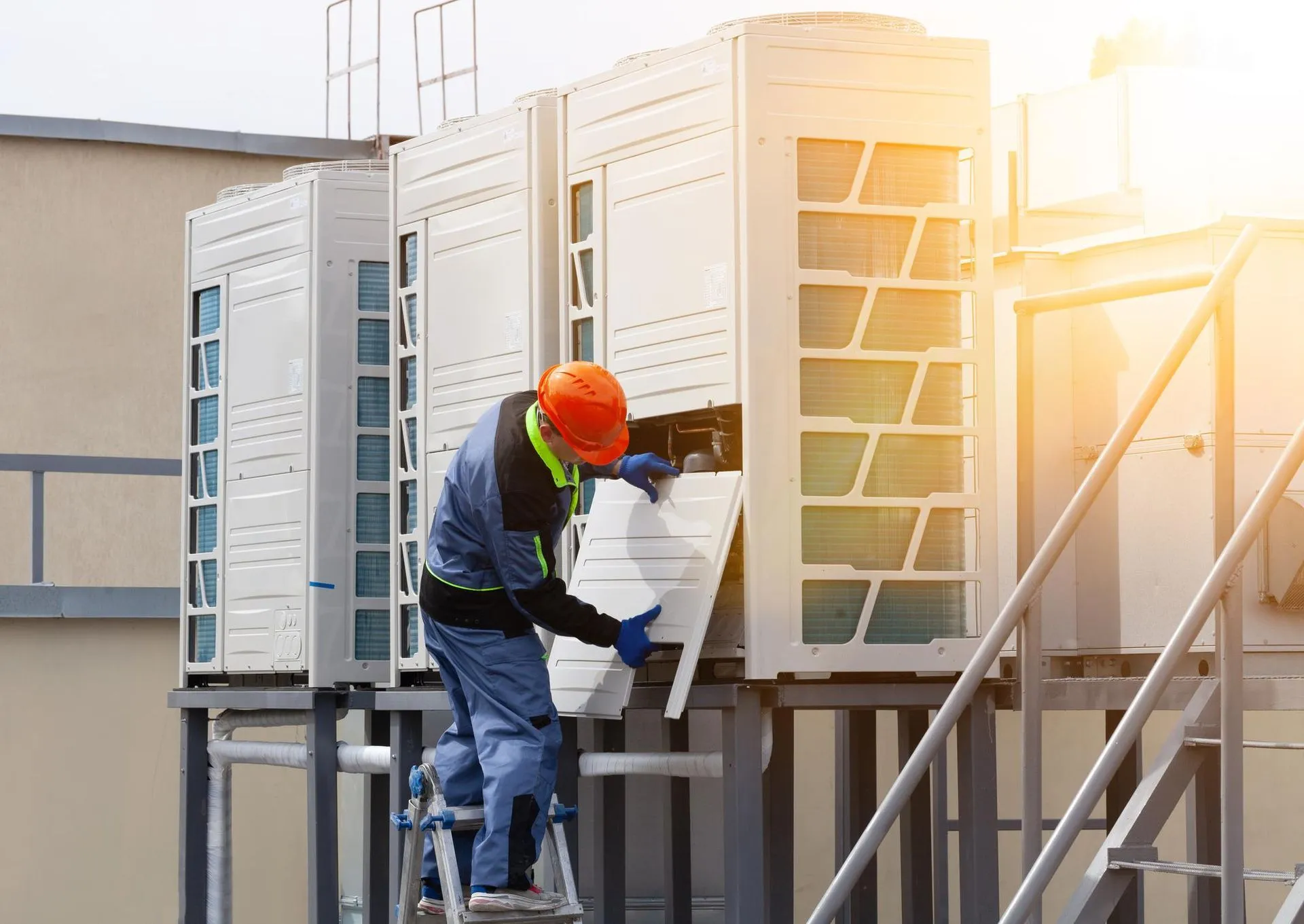A skilled technician from Reid Heating & Air is working on an air conditioner on the roof of a building.
