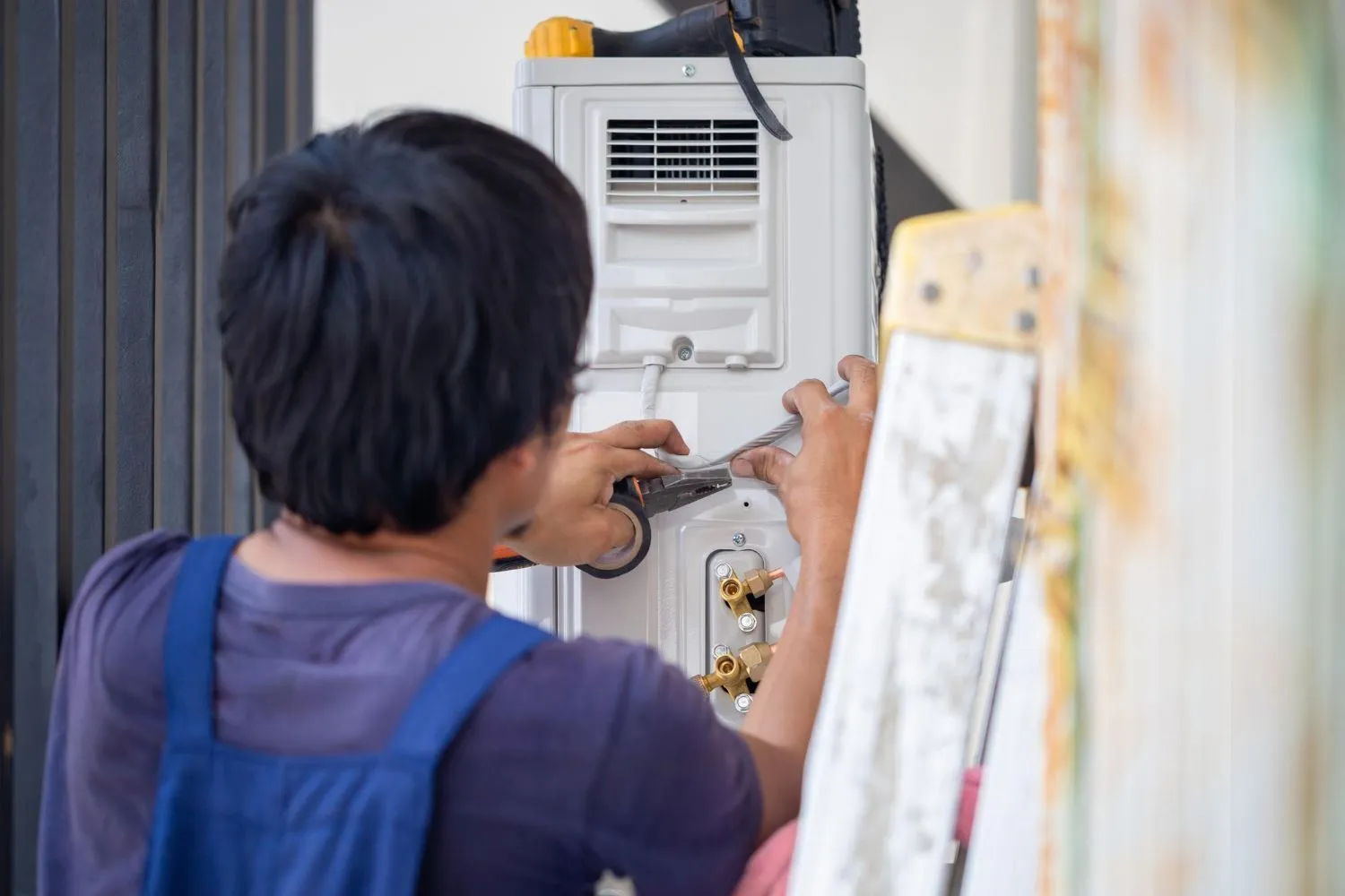 A man from Reid Heating & Air is working on an air conditioner.